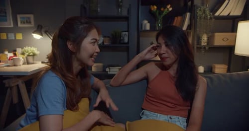 Two Young Women Chatting Comfortably on Couch Indoors