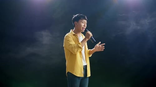 Young Adult Man Singing into Microphone on Stage