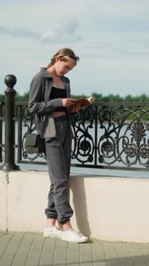 Woman Reading Book Outdoors in Urban Setting