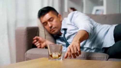 Man Drinking Whiskey Lying on Couch at Home