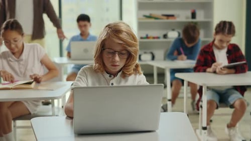 Schüler, der den Computer benutzt, sitzt und macht Hausaufgaben in der Klasse während des Informatikunterrichts