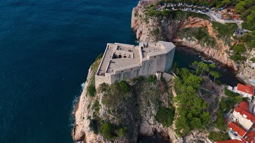 aerial high angle landscape panning down over fort lovrjenac on Adriatic cliff coast in sunlight