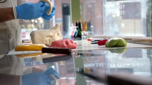 Un pâtissier découpant du caramel avec des ciseaux sur une table dans une pâtisserie