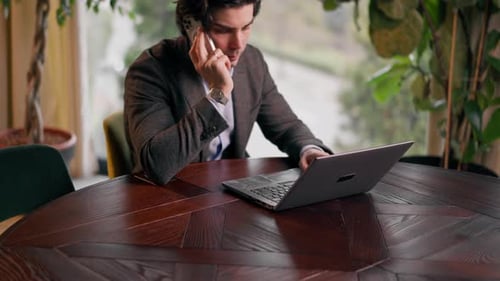 a serious man a businessman works at a laptop in the office communicates with colleagues