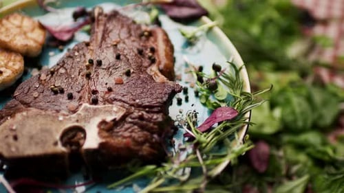 Gegrilltes T-Bone-Steak, das sich auf dem Tisch dreht, mit frischem Grün
