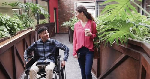 Two happy diverse creative colleagues in discussion in casual office, slow motion