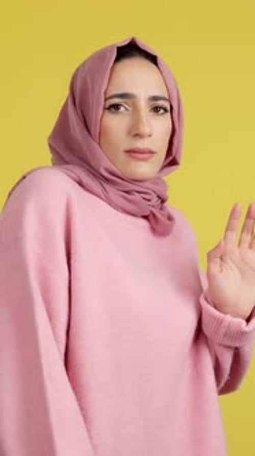 Woman in headscarf says no with her hands