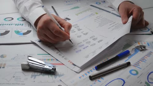 Hands Reviewing Business Reports at Desk