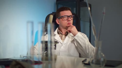Scientist Thinks at Desk with Laboratory Equipment