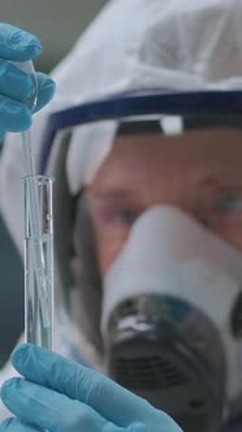 Científico o investigador que lleva un traje de protección total para materiales peligrosos y un respirador que realiza pruebas de líquidos