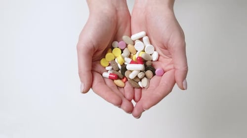 Píldoras coloridas en manos abiertas que exploran las opciones de atención médica