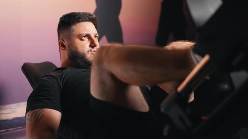 Strong young bearded caucasian man bodybuilding workout training in leg press in dark fitness gym tr