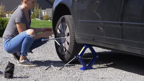 Woman Changing Tire on Vehicle with Lug Wrench