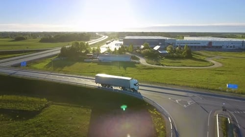 Aerial View of White Semi Truck with Cargo Trailer Passing Highway Overpass/ Bridge. Eighteen Wheel