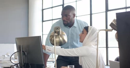 Colaborando no projeto, colegas discutindo o trabalho no computador em um escritório moderno