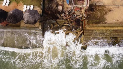 Ocean waves taking over city shore line and destroying it, aerial view