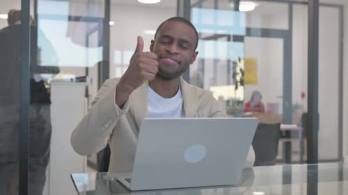 Smiling Man Working on Laptop Giving Thumbs Up