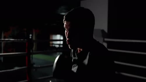 Man Training and Boxing in Dark Ring