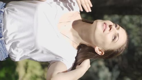 Vidéo verticale de La femme suffoque à cause du temps chaud et ensoleillé à l'extérieur.