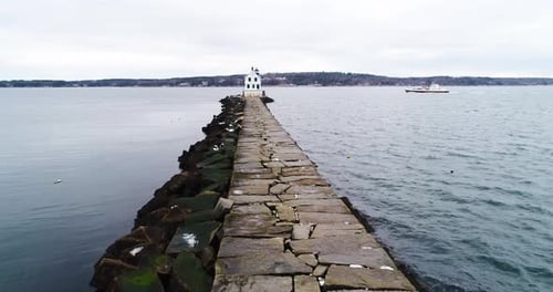 Quebra-mar de pedra comprida que se estende até o Mar Cinzento com farol distante