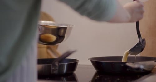 Pouring Pancake Batter Into Frying Pan in Kitchen