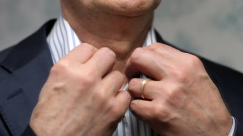 Man Buttoning Striped Shirt in Blue Suit, Close-Up