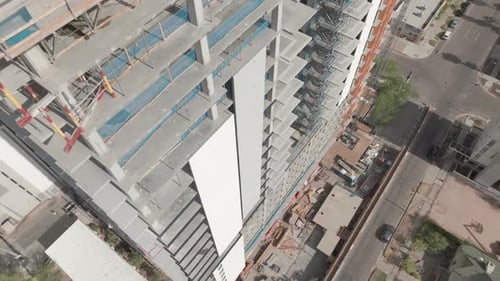 Imágenes de Zumbido descendentes de un hotel en construcción, moviéndose por la pared exterior del hotel, hacia abajo