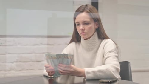 Woman Counting One Hundred Dollar Bills at Table