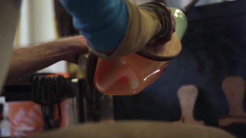 Glass Blower Shaping Hot Glass in Workshop