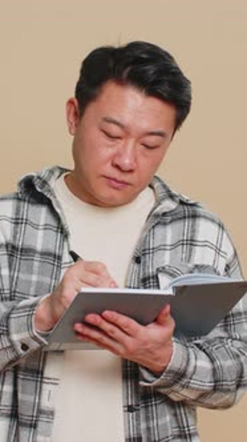 Man Writing in Notebook and Pondering