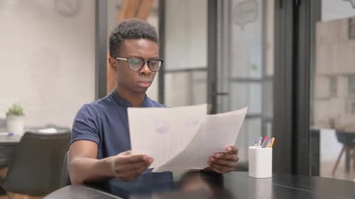 Young African Man Reading Documents in Office