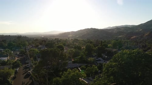 Gorgeous aerial push by palm tree over mountain town during sunset
