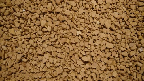 Slider up and scooping soluble coffee granules with a spoon. Dolly slider, close up.