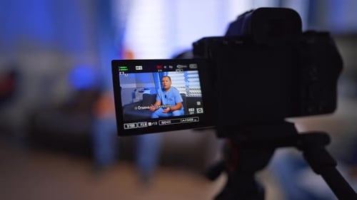 Confident Caucasian male doctor making a video. Camera records content for medical vlog.