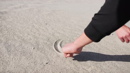Jungenhand zeichnet im Spätsommer ein Herz am Strand