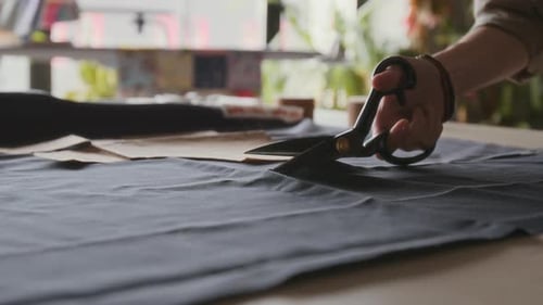 Hands Cutting Fabric with Scissors in Workshop