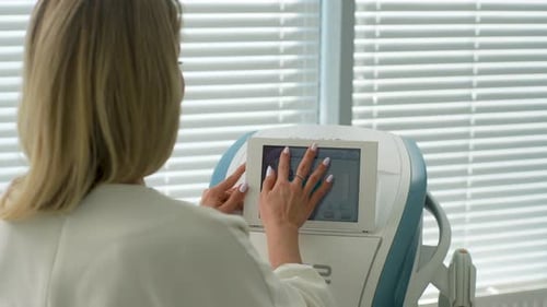 Closeup Rear View of Unrecognizable Female Beautician Typing on Screen of Device in Beauty Salon