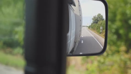 View to Side Mirror of Truck with Empty Road at Background Lorry Driving Through Countryside on