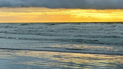 Golden sunset over the ocean with reflections on a beach