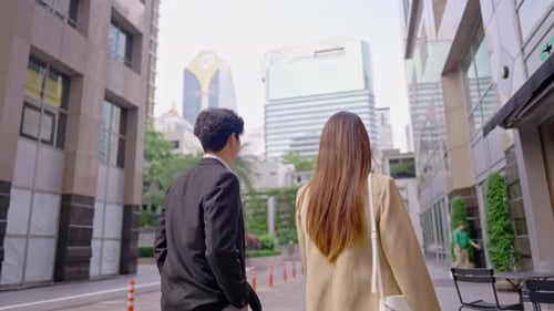 Rear view of businessman and woman partner working outdoors in the city.