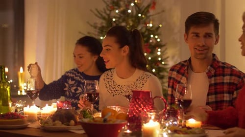 Friends Gather Around Dinner Table with Christmas Tree