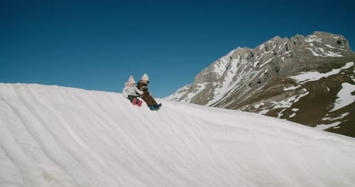 Bruder und Schwester haben Spaß auf dem verschneiten Berghügel in den Winterferien