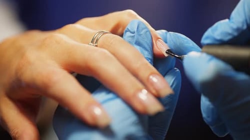 Une manucure applique une base de gel sur un ongle dans un salon de beauté