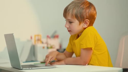 Focused Schoolboy Using Laptop for Online Education at Home