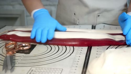 Un pâtissier colle du caramel liquide chaud rouge et blanc pour créer des sucettes artisanales