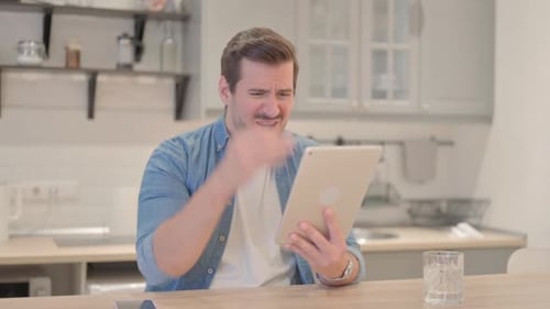 Man Reacting Negatively to Tablet at Home