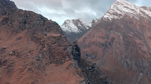 Rugged mountain peaks with snow under a soft sky at dawn, a sense of serene wilderness