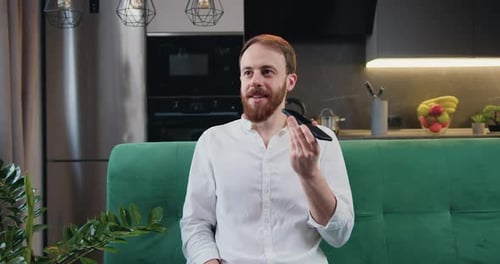 Attaractive, un homme assis dans la cuisine, tient son téléphone intelligent et parle sur haut-parleur. Message audio enregistré par un homme