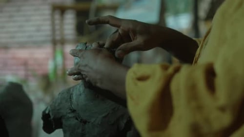 Artist sculpting clay with focused hands in a creative studio setting