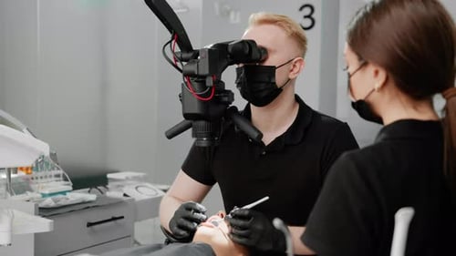 At the dental clinic a dentist examines a patient with a toothache under a microscope